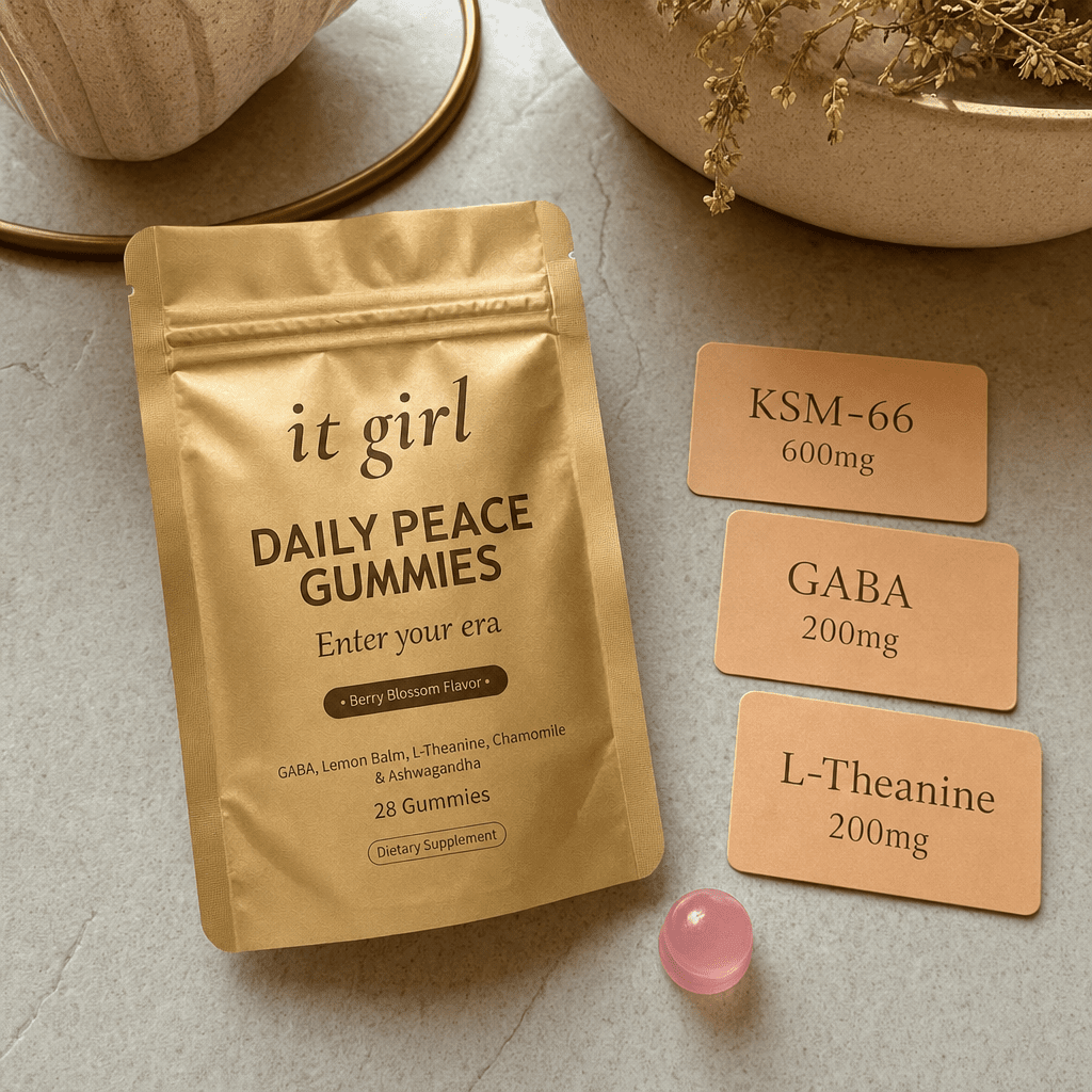 Product reveal: three warm dose cards reading GABA 200mg, L-Theanine 200mg, KSM-66 600mg beside the real gold It Girl Daily Peace pouch and a single gummy on a cream surface, the named studied stack