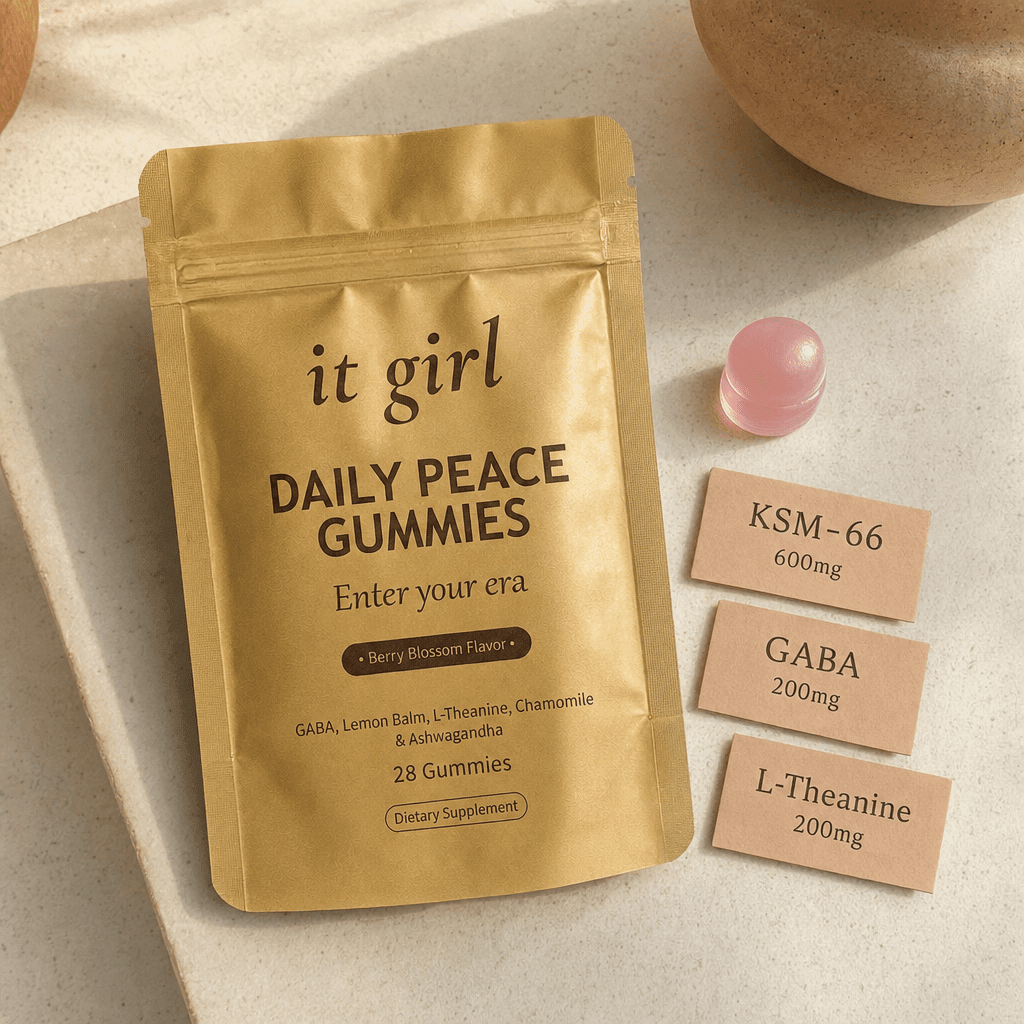 Product reveal: three warm dose cards reading GABA 200mg, L-Theanine 200mg, KSM-66 600mg beside the real gold It Girl Daily Peace pouch and a single gummy on a cream surface, the named studied stack