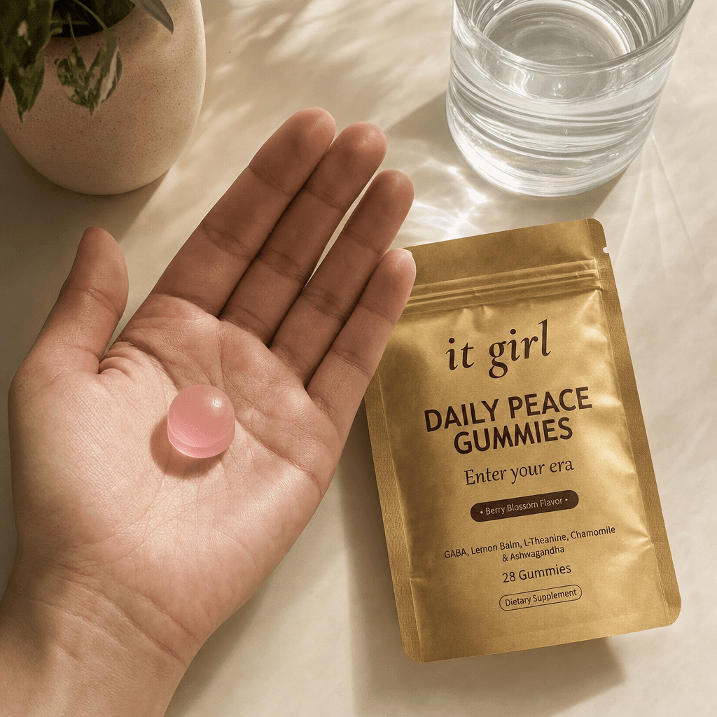 Open palm holding a single pink Daily Peace gummy beside the gold pouch on a warm cream surface, the studied calm signal revealed