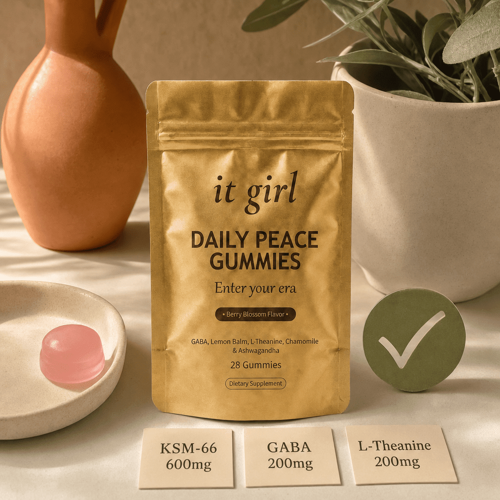 The real matte-gold It Girl Daily Peace pouch with a green checkmark, a single pink gummy, and three dose cards reading KSM-66 600mg, GABA 200mg, L-Theanine 200mg on a warm cream surface, the piece the routine was missing